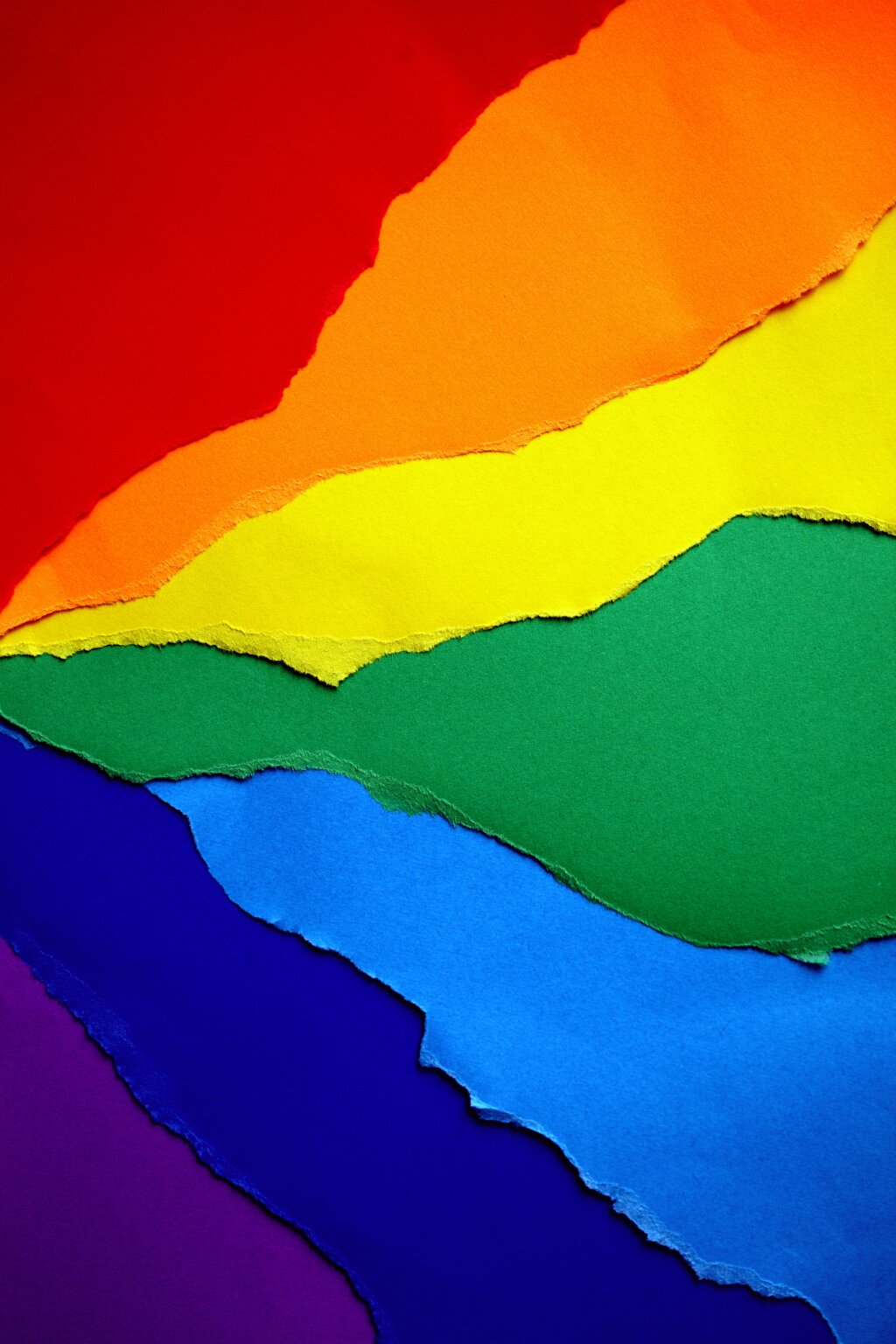 Een regenboogvlag gemaakt van gescheurde papieren vellen.