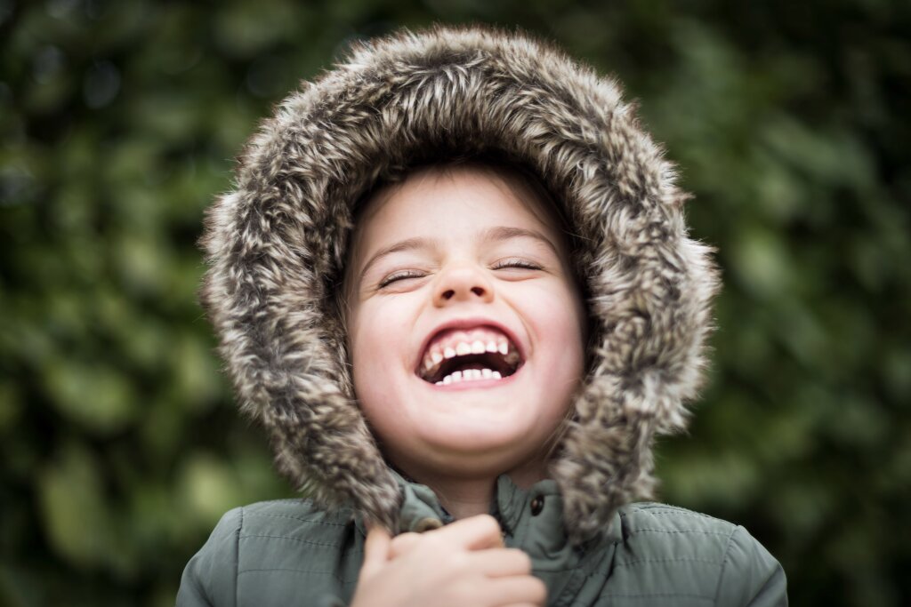 Een vrolijk lachend kindje met een bontkraag.